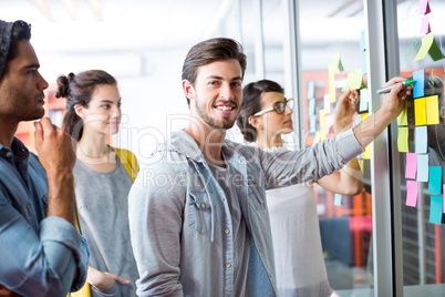 Portrait of smiling executives writing on sticky notes