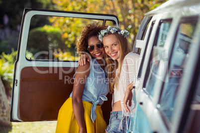 Portrait of two female friends standing near campervan