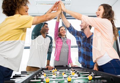 Executives giving high five while playing table football