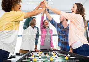 Executives giving high five while playing table football