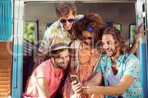 Group of happy friend using mobile phone in campervan