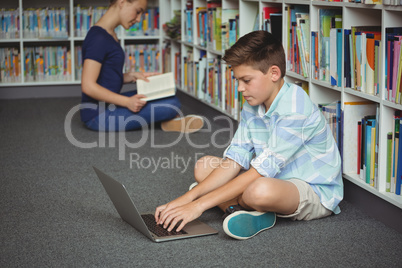 Schoolboy using laptop in library