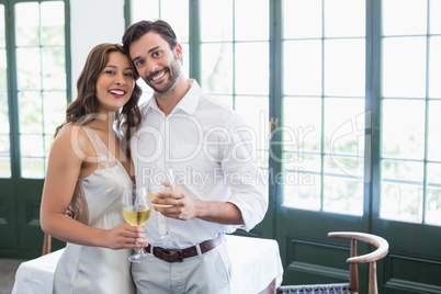 Happy couple hugging while holding wine glasses