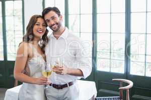 Happy couple hugging while holding wine glasses