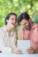Couple laughing while using digital tablet