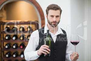 Male waiter holding wine glass and wine bottle in the restaurant