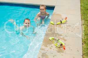 Smiling boy and girl playing in swimming pool