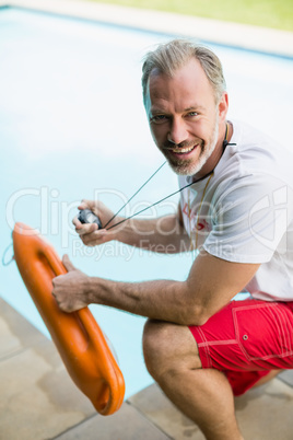 Portrait of smiling swim coach holding stop watch and inflatable tube
