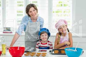 Smiling mother and kids preparing cookies in kitchen