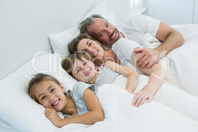 Happy family lying together on bed in bedroom at home