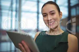 Businesswoman smiling while using digital tablet
