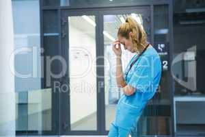 Upset female doctor standing in corridor