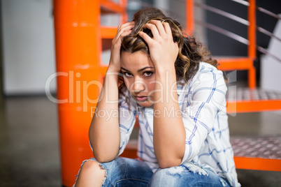 Portrait of sad female executive sitting on staircase