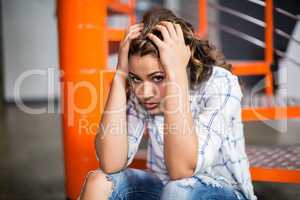 Portrait of sad female executive sitting on staircase