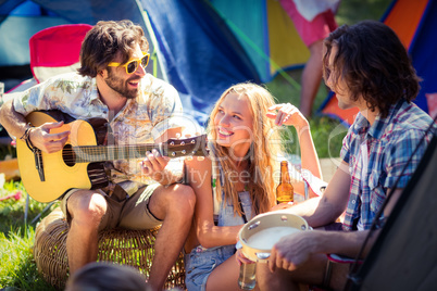Friends having fun and playing music at campsite