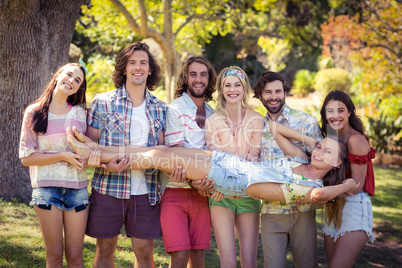 Group of friends lifting woman at campsite