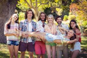 Group of friends lifting woman at campsite