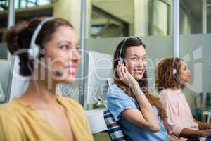 Smiling female customer service executive talking on headset at desk