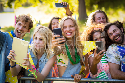 Friends clicking pictures from their mobile phones and digital tablet