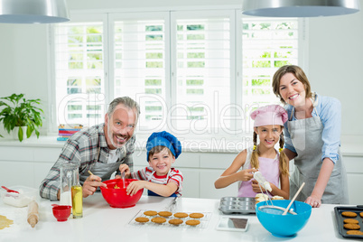 Smiling parents and kids preparing cookies in kitchen