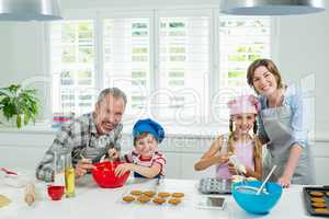 Smiling parents and kids preparing cookies in kitchen