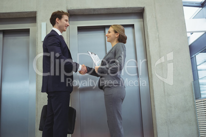 Businesspeople shaking hands near elevator
