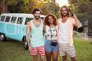 Three friends standing together near campervan