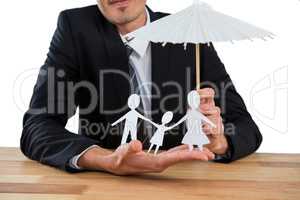 Businessman holding an umbrella protecting a family