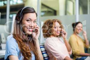 Portrait of female customer service executives talking on headset at desk