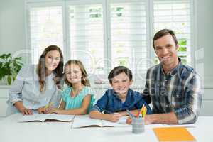 Portrait of smiling family studying together in living room