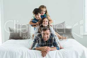 Portrait of smiling family playing on bed in bedroom