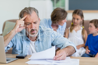 Worried man calculating bills on the laptop in living room