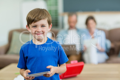 Portrait of smiling boy using digital tablet in living room