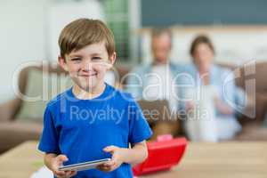 Portrait of smiling boy using digital tablet in living room