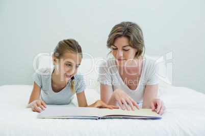 Mother and daughter lying on bed and reading book Mother and daughter lying on bed and reading book