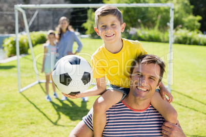 Smiling father carrying his son on shoulder at the park