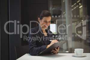 Happy businesswoman writing on clipboard