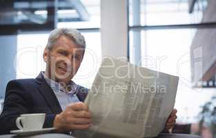 Businessman reading newspaper while having coffee