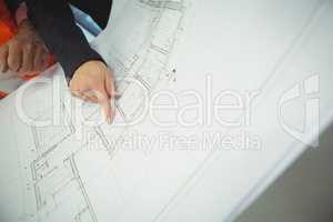 Hand of businesswoman pointing at area on blueprint