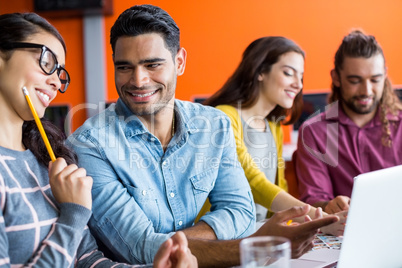 Smiling graphic designers discussing over laptop in meeting