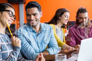 Smiling graphic designers discussing over laptop in meeting