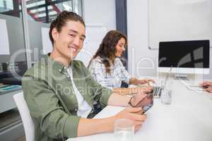 Smiling executive using laptop and digital tablet in conference room