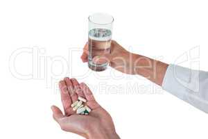 Executive holding glass of water and medicines