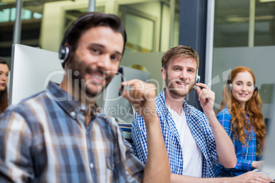 Portrait of smiling customer service executives talking on headset at desk