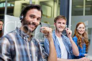 Portrait of smiling customer service executives talking on headset at desk