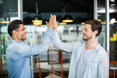 Two colleagues giving high five in office