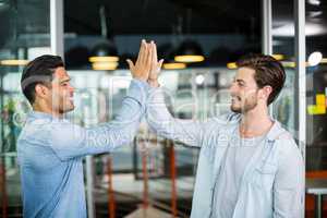 Two colleagues giving high five in office