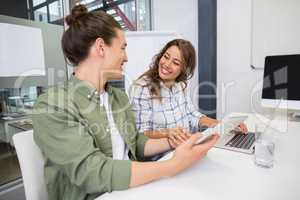 Smiling executive using laptop and digital tablet in conference room