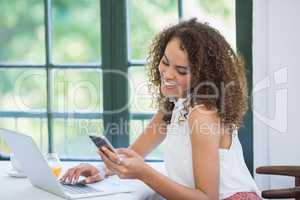 Beautiful woman using mobile phone and laptop