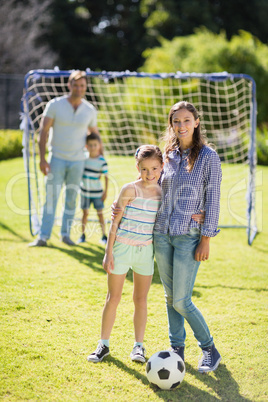 Smiling mother and daughter standing together at the park